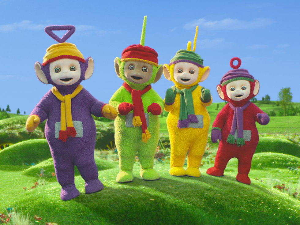 All four Teletubbies dressed in winter clothes outside while it is snowing.