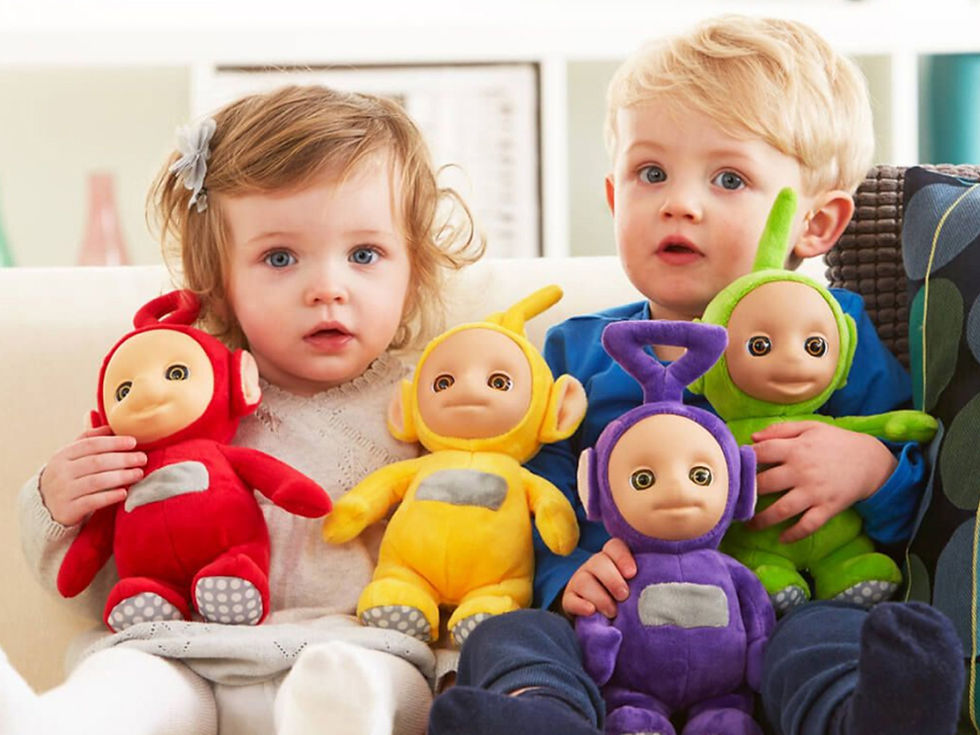 two children holding colourful Teletubbies plush toys on their laps sitting on a couch