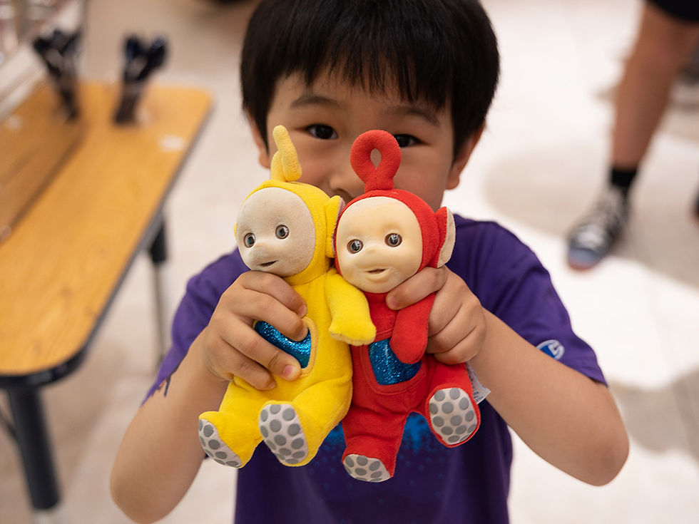 a child holding yellow and red Teletubbies plush toys in their hands